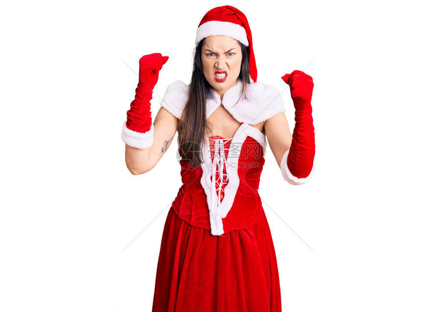 年轻美丽的白种女人穿着圣诞老人服装愤怒和疯狂地举起拳头沮丧和愤怒图片