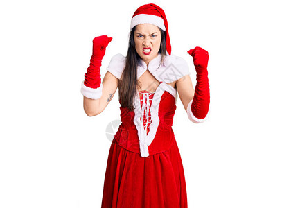 年轻美丽的白种女人穿着圣诞老人服装愤怒和疯狂地举起拳头沮丧和愤怒图片
