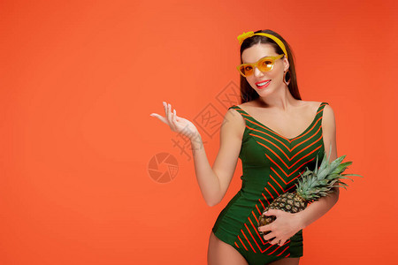 用菠萝手对准妇女前视线微笑和望着在橙色上被图片