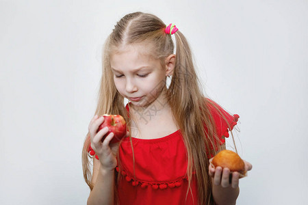 扎着马尾辫的金发少女吃着一个红苹果图片