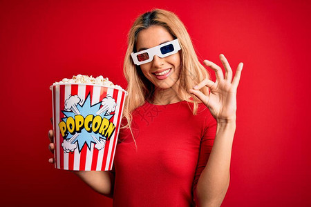 看电影的年轻金发美女以3D杯眼镜吃爆米花作为零食用手指做好牌子图片