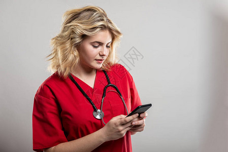 护士穿戴在智能手机上用灰色工作室背景和复制空间广告区的红色抹黑文图片