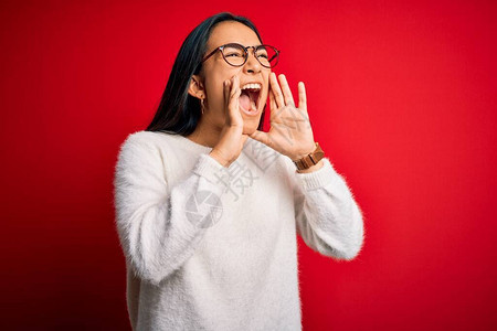 红色背景下身穿休闲毛衣和眼镜的年轻美丽亚洲女双手捂图片