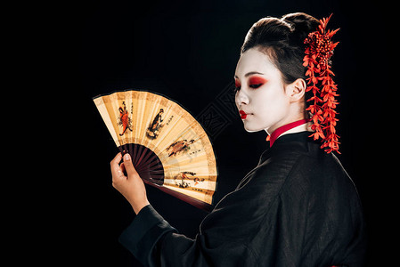 黑和服舞艺妓红花在头发上看着传统的亚洲手风扇在图片