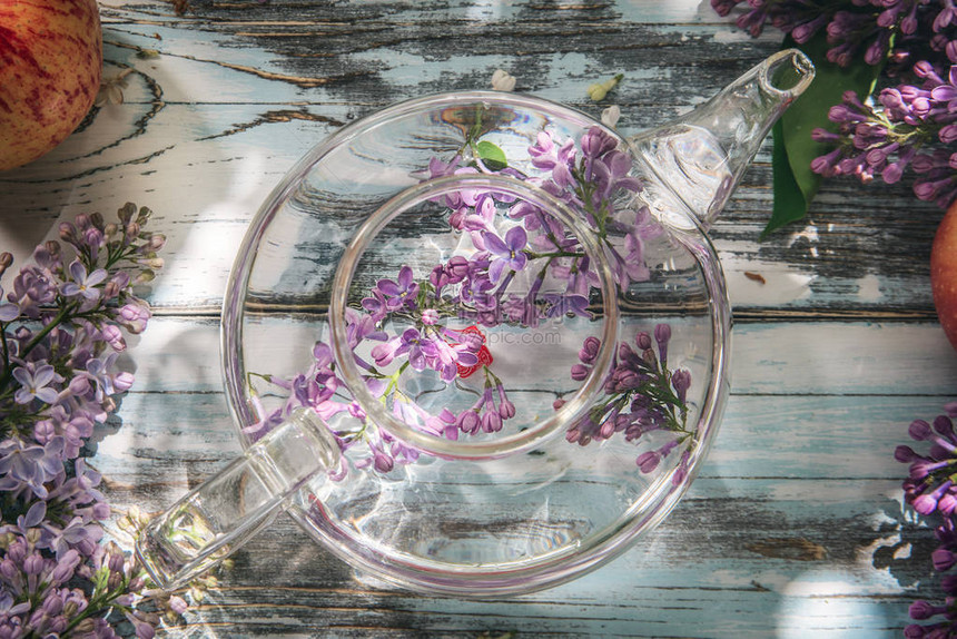 蓝色的旧木制桌子上透明的玻璃茶壶里花朵图片