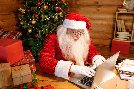 圣诞老人服装和白手套在圣诞节前夕写好名单的同时敲打笔记本电图片