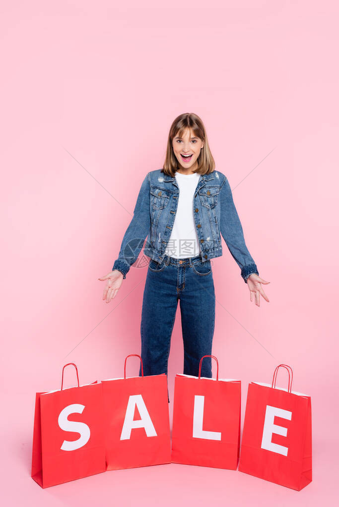 年轻女亲手用粉红背景的销售信件对着购物图片