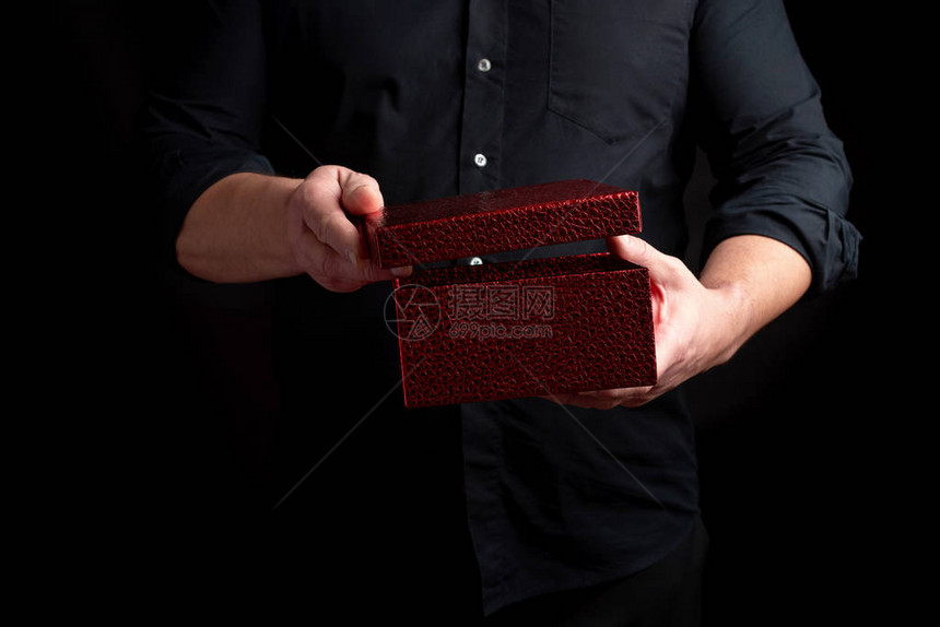 穿黑衬衫的成人男子拿着一个纸板红礼盒图片