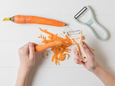 孩子用木桌上的特殊刀具清洗和切胡萝卜用一把特殊的图片