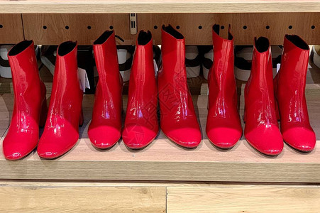 红色女式高跟踝靴鞋店货架上的明亮女背景图片