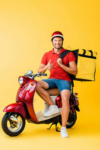 带背包坐在红色摩托车上在黄色上举图片