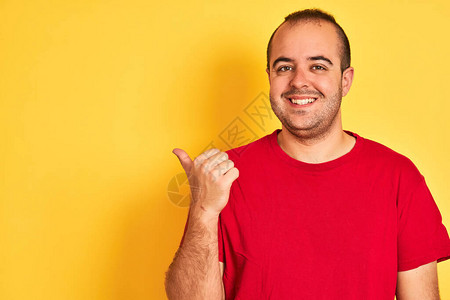 身穿红色临时短袖T恤的年轻人站在孤立的黄色背景指角上图片