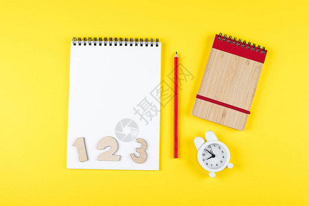 回到学校样机概念上学时间最小的概念记事本铅笔黄纸背景上的闹钟平躺顶视图片