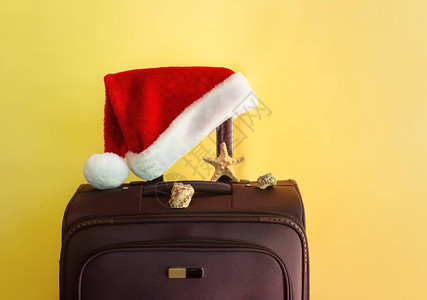 棕色手提箱海星贝壳和圣诞老人帽子的黄色背景图片