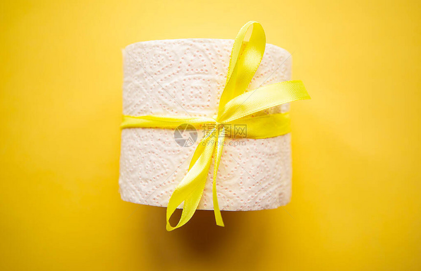 卫生纸卷包裹在黄色背景的礼品蝴蝶结中Covi图片