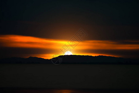 剪影山与夕阳的天空和湖边的乌云图片