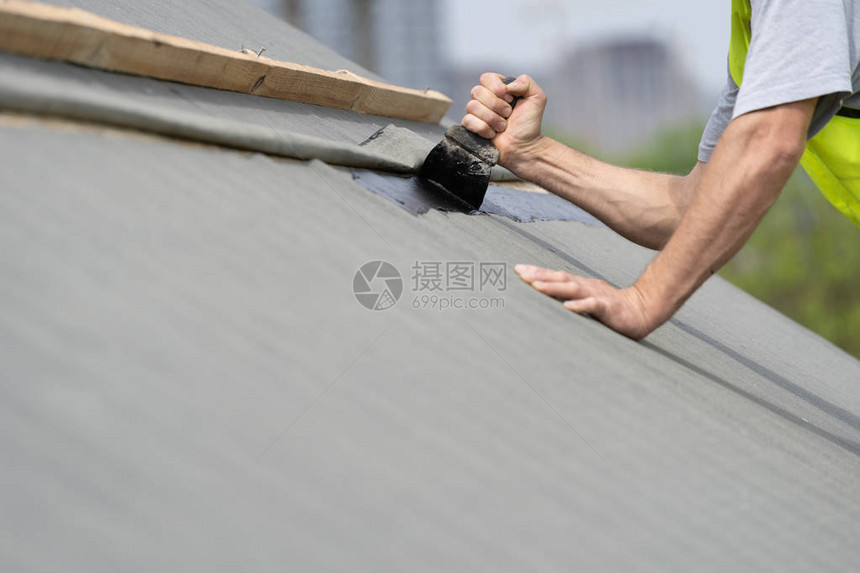 在建房屋的概念裁剪无法辨认成熟和专业的屋顶修复大师现代建筑中使用焦油抹刀和特殊防图片