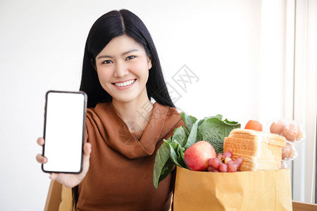 亚洲女拥有智能手机在网上订购食物图片