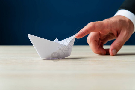 一个商人的手指向前推纸造成折纸船背景图片