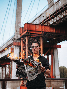 身戴太阳镜的人读着燃烧的报纸图片