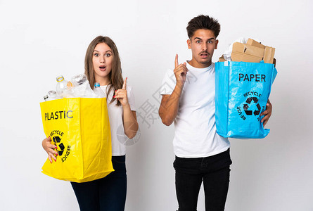 年轻夫妇拿着满袋塑料和纸的袋子图片