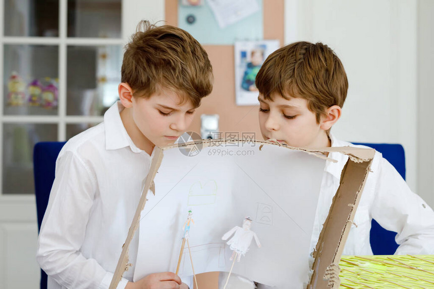 两个小学生男孩制作纸娃剧院快乐的孩子和朋友在家里隔离期间创造人物和表演舞台剧活跃的创意兄弟图片