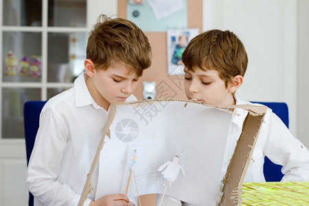 两个小学生男孩制作纸娃剧院快乐的孩子和朋友在家里隔离期间创造人物和表演舞台剧活跃的创意兄弟背景图片