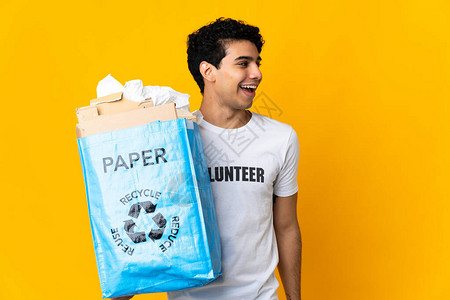 年轻委内瑞拉男子拿着一个回收袋满纸的回收纸图片