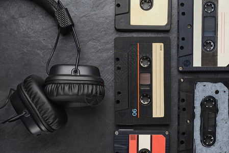 石板背景上的黑色入耳式机和音频磁带紧凑盒式磁带图片