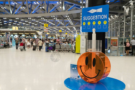 以乘客为背景在国际机场大厅放置乘客建议的选票笑脸塑料盒特写背景图片