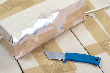盒子上被损坏的包装物和一把蓝手刀在后图片