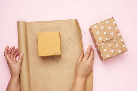 包印造纸两只手包礼物印在粉红背景的棕色K背景