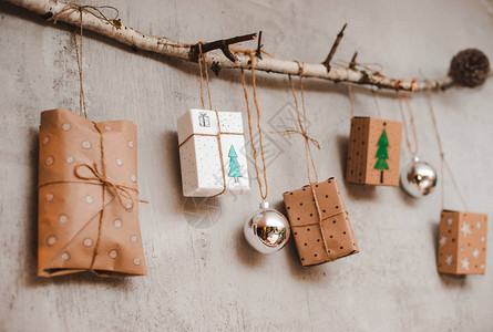 用牛皮纸和手工制作的装饰品包装的圣诞礼物挂在一根绳子上图片