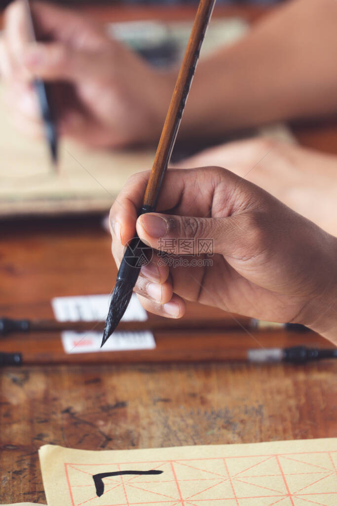 一位在传统书法硕士中文写作课程中手持墨水刷的学生的手图片