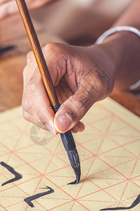 一位在传统书法硕士中文写作课程中手持墨水刷的学生的手图片