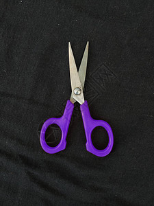 黑色背景上孤立的钢和紫色小单剪刀的特写背景图片