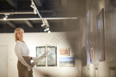 女艺术专家在现代美术馆或博物馆复制空间对绘画进行评图片