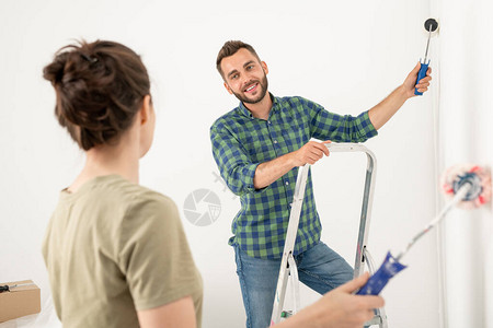 微笑着的英俊年轻男子在与妻子一起改造房间的同时图片