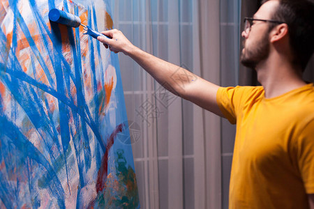 抽象艺术家在艺术工作室的画布上用滚筒绘画图片