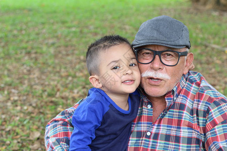 快乐的祖父和孩子在绿草背景上拥图片