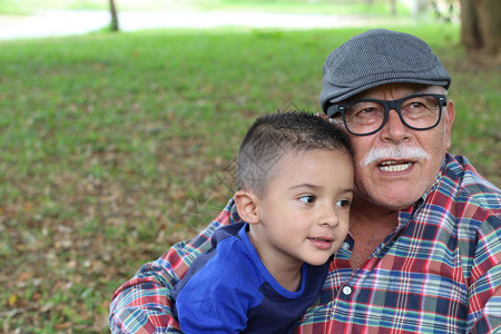 快乐的祖父和孩子在绿草背景上拥图片