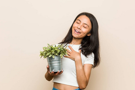 年轻的亚洲女人拿着植物大笑大喊叫地图片