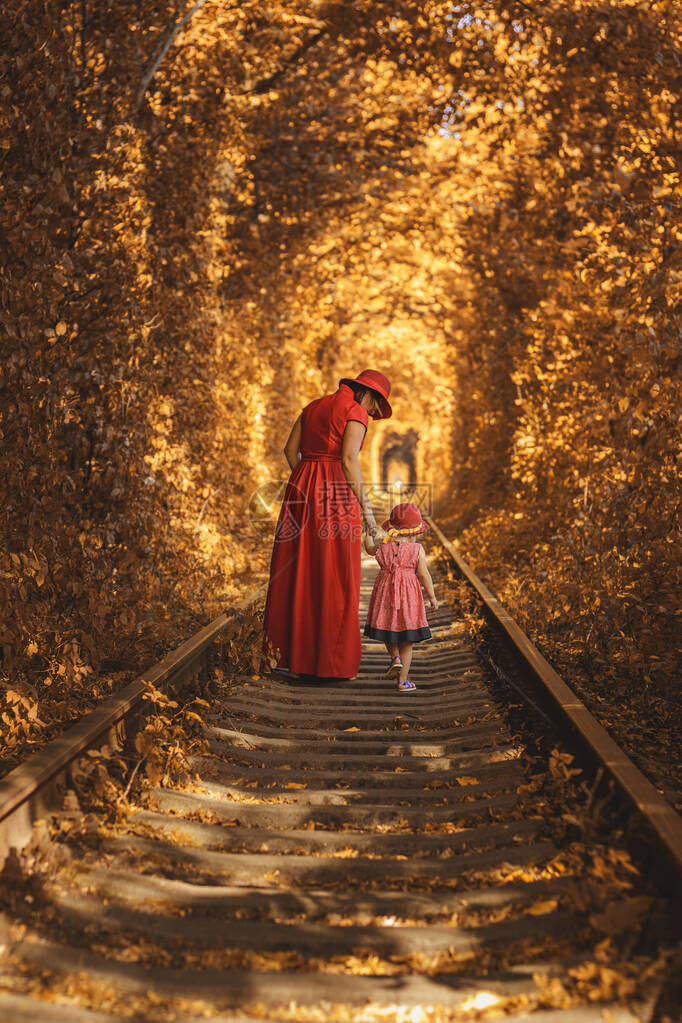 妈带着女儿戴着红帽子在爱的隧道里走在秋天2019图片
