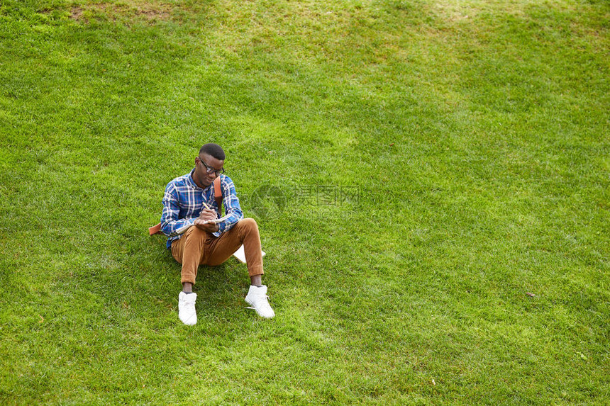 年轻非裔美国人坐在校园绿上图片