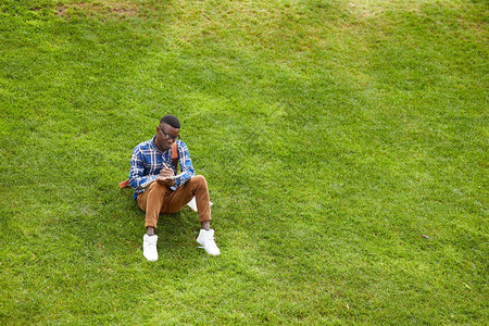 年轻非裔美国人坐在校园绿上图片