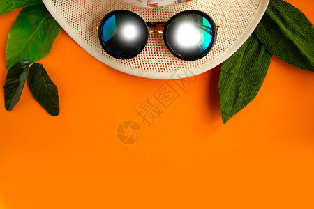 浅橙色背景的草帽和太阳镜最低概念暑假概念复制空图片