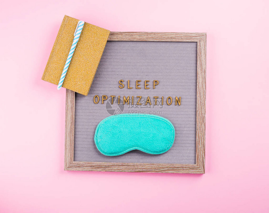 在带有水绿色睡眠面具的木制字母板上组成的睡眠优化文本短语用于跟踪习惯的黄金日记睡眠日志粉红色背景中更好的健康图片