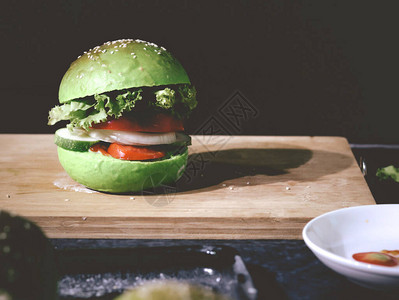 汉堡包为木制切纸板上的绿色蔬菜面包制作图片