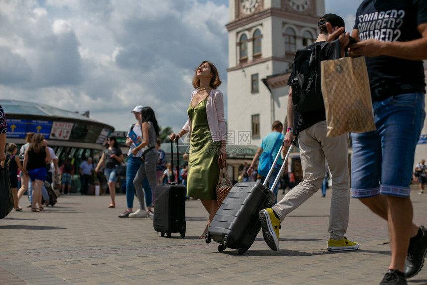 带着一个手提箱的年轻黑发小黑发在广场车站周围到处是乘客的背景下图片
