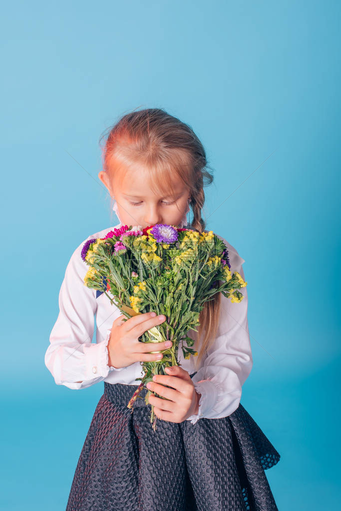 美丽的年轻一年级学生的画像一年级女孩在工作室里用鲜花学校弓工作室肖像回到学校复制空间学校工作室摄影系列棕图片